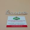 Monogramme (badge, logo) de tablier VESPA en aluminium (Long 120 mm entraxe des fixations 99 mm)